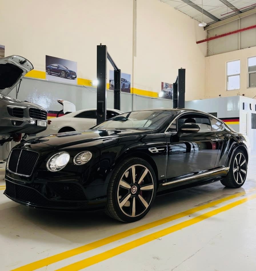 Technician inspecting a vehicle engine bay in a workshop